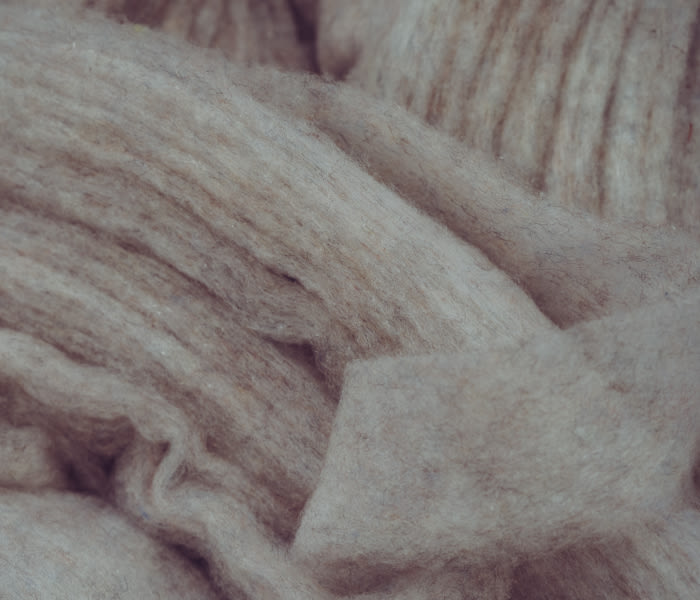 Close-up of Mammut beige wool fabric showcasing its soft texture and natural wrinkles, ideal for high-performance sports and mountaineering gear.
